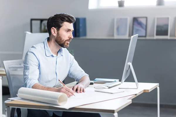 Experienced architect working on project plan of house paints, man in office at work