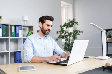 Ofiste çalışma ortamı. Genç bir iş adamının portresi, ekonomist, büroda çalışan bir yönetici, bir dizüstü bilgisayar, kağıtlarla çalışıyor. Belgeler.