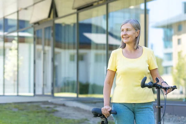 Aktive Rentnerin Geht Mit Fahrrad Vor Ein Modernes Gebäude — Stockfoto