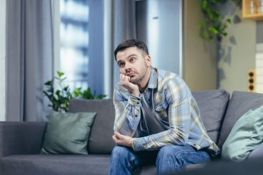 Yakışıklı bir gencin portresi. Beklemek, sıkılmak, düşünmek. Evde, kanepede oturuyor, kafasını elinde tutuyor, depresyon ve karantinayı düşünüyor.