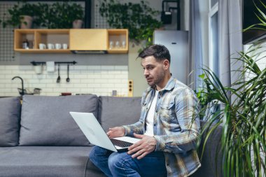 Evde dizüstü bilgisayarla çalışan genç bir adam. Görüntülü konuşma. Kanepede oturuyorum..