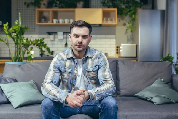 Kanepede oturan bir adam kameraya bakıyor, bir hamal video görüşmesinde konuşuyor.