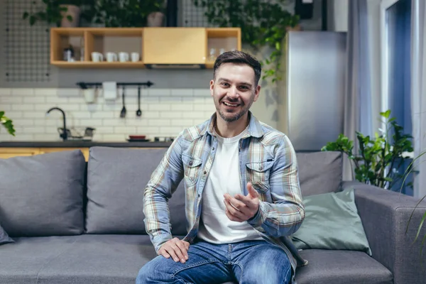 Kanepede oturan bir adam kameraya bakıyor, bir hamal video görüşmesinde konuşuyor.