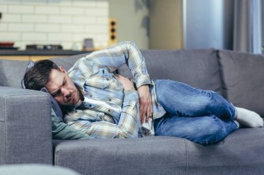 Evdeki kanepede yatan hasta adamın şiddetli karın ağrısı var.