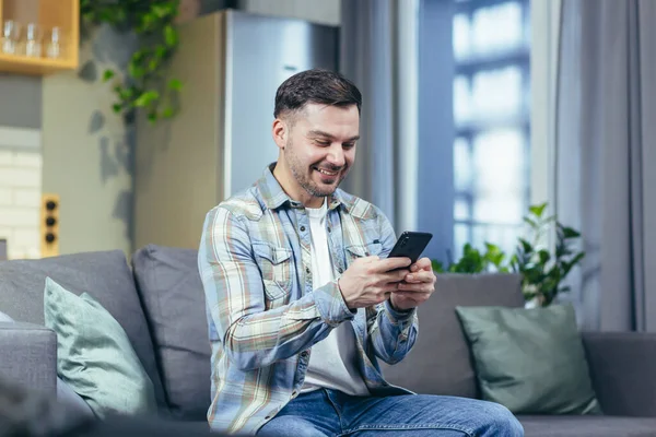 Happy Man Looks Phone Home Rejoices Success Victory — Stock Photo, Image