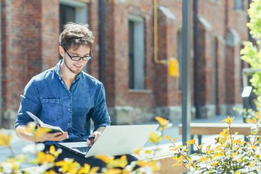 Genç, yakışıklı, yaratıcı, gözlüklü, dizüstü bilgisayarlı bir bankta oturan genç bir mimar. Proje üzerinde çalışır, notlar, çizimler ve grafikler hazırlar..