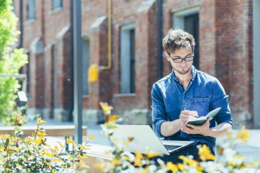 Genç, yakışıklı, yaratıcı, gözlüklü, dizüstü bilgisayarlı bir bankta oturan genç bir mimar. Proje üzerinde çalışır, notlar, çizimler ve grafikler hazırlar..