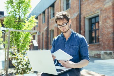 Genç, yakışıklı, yaratıcı, gözlüklü, dizüstü bilgisayarlı bir bankta oturan genç bir mimar. Proje üzerinde çalışır, notlar, çizimler ve grafikler hazırlar..