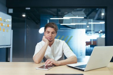 Ofiste düşünen genç bir adam, iş planı ve başlangıç geliştirme stratejisi üzerine dizüstü bilgisayarla çalışan bir iş adamı