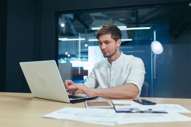 Ofiste dizüstü bilgisayarla çalışan ciddi bir iş adamı.