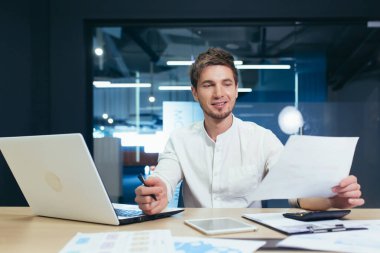 Genç yakışıklı iş adamı, yönetmen, patron imzalar ve başarılı bir iş anlaşması yapar. Belgeleri elinde tutuyor. Ofisteki masasında sırıtarak bekliyor.