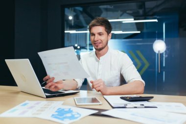 Genç yakışıklı iş adamı, yönetmen, patron imzalar ve başarılı bir iş anlaşması yapar. Belgeleri elinde tutuyor. Ofisteki masasında sırıtarak bekliyor.