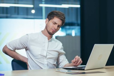 İş yerinde yorgunluk hissiyatı. Genç bir ofis çalışanı, serbest çalışan, bilişim uzmanı yorgun, arkasını kollayan, acı çeken, rahatsızlık duyan. Dinlenmeye ihtiyacı var.