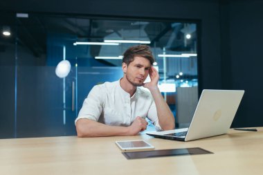 Kendimi kötü hissediyorum. Serbest çalışan genç bir adam, yönetmen, menajer başını tutuyor, başı ağrıyor, yorgun, hasta. Ofiste bir dizüstü bilgisayarla oturuyor.