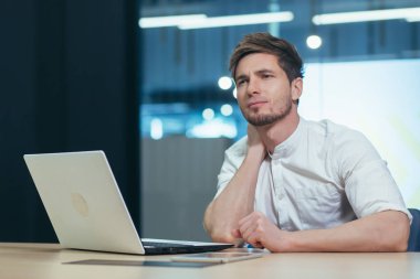 İş yerinde yorgunluk hissiyatı. Genç bir ofis çalışanı, serbest çalışan, bilişim uzmanı yorgun, boynunu tutan, acı çeken, rahatsızlık duyan. Dinlenmeye ihtiyacı var.