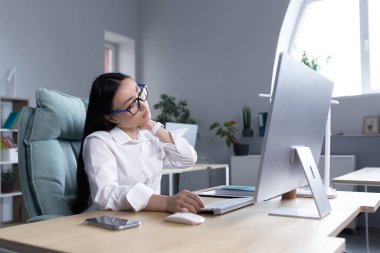 Aşırı yorgun Asyalı kadın ofis çalışanı, boyun ağrısı, elle boyun kası masajı, bilgisayardaki kadın çalışan..