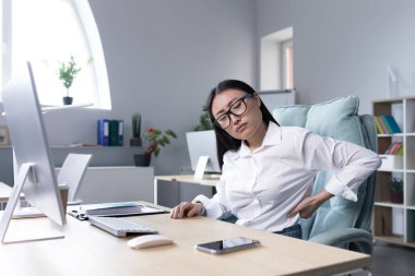 Sırtına masaj yapan yorgun kadın ofis çalışanı, Asyalı iş kadınının sırtı ve sırt ağrısı var..