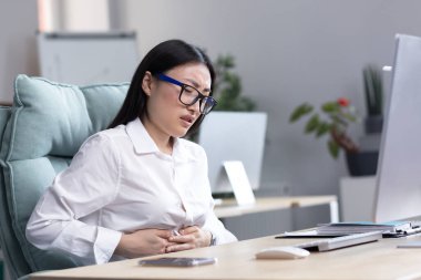 Asyalı iş kadını ofiste hasta, şiddetli mide ağrısı, mide bulantısı ve ishal..