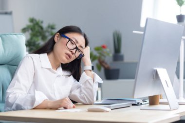 Üzgün bir Asyalı iş kadını yeteneklerinden umudunu kesmiş, depresyonda ve bilgisayarın ofisinde çalışıyor..