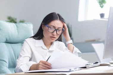 Teslim tarihleri yakıyor. Genç ve güzel Asyalı iş kadını endişeli, büroda oturuyor, elinde belgeler var. Onları gösteriyor, elleriyle başını tutuyor, ne yapacağını bilmiyor.