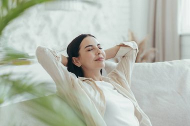 Bir kadın evinde dinleniyor, yakın plan bir fotoğraf, elleri başının arkasında bir portre, kanepede oturuyor ve uyukluyor.