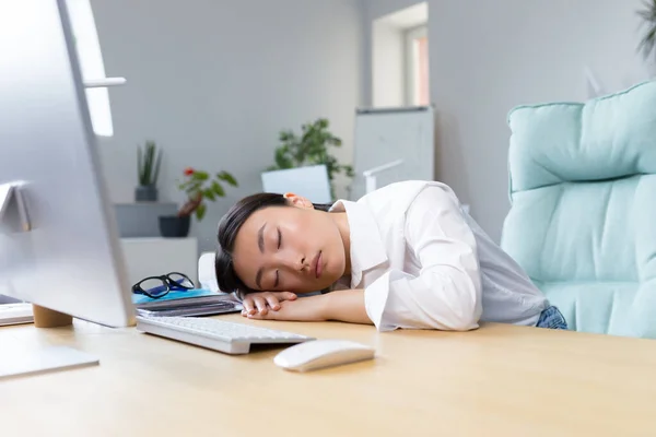 Young Asian businesswoman fell asleep at the desk on her hands in the office, tired, routine, boring work, needs a break.