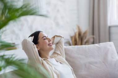 Güzel esmer kadın gün boyunca gözleri kapalı dinleniyor, hayal kuruyor ve kanepede uyuyor.