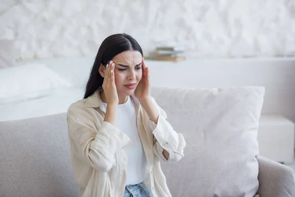 Sick Woman Sitting Sofa Home Holding Her Head Her Hands — стоковое фото