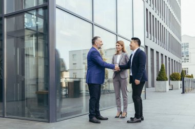 Business meet, colleagues happy team meet outside office, greet shake hands, diverse employees in business suit, man and woman business people