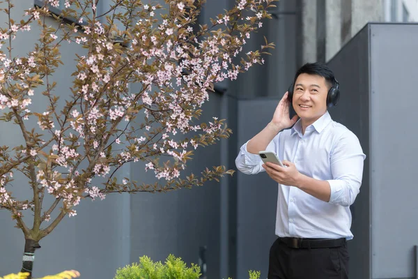 Cheerful Smiling Successful Asian Business Man Listening Music Using Smartphone — Foto de Stock