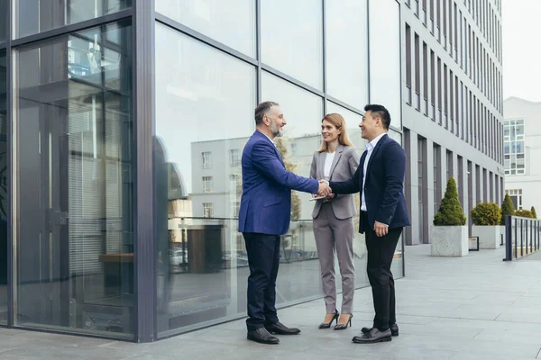 Business meet, colleagues happy team meet outside office, greet shake hands, diverse employees in business suit, man and woman business people