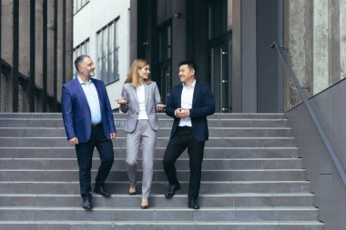 Diverse business team man and woman walking together on stairs outside office building, business people take a walk on break and have fun talking