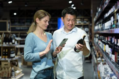 A young married couple, a diverse man and a woman, together in a supermarket choose an alcoholic wine, dissatisfied with the choice, use an application on the phone to scan goods and bottles