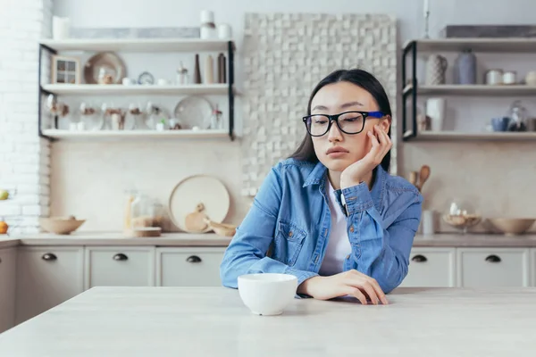 Грустная Думающая Женщина Кухне Депрессивная Азиатка Сидящая Столом Дома Молодая — стоковое фото