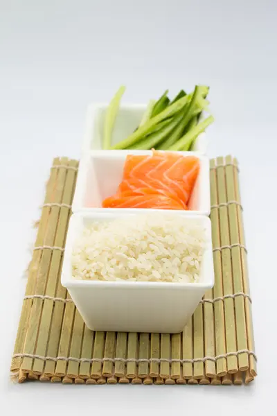 Rice salmon and sliced cucumber in white dish on bamboo mat — Stock Photo, Image