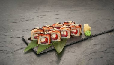 Suşi, ton balığı, yılan balığı, unagi ve avokado ile birlikte siyah taş tabakta yuvarlanıyor..