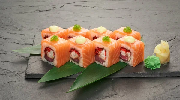 Involtini di sushi con tonno salmone anguilla unagi e avocado su un piatto di pietra nera. — Foto Stock
