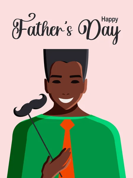 Happy Father\'s Day. Modern postcard with a young African American man in a tie, who, for humor, holds a paper mustache in his hand, who became a father. Vertical pink background.