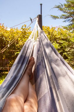 Mujer descansando en una reposera tomando sol en sus piernas