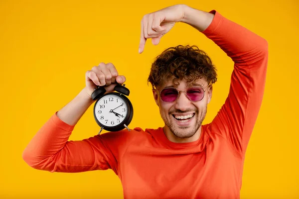 Jovem Bonito Sorrindo Homem Aponta Para Despertador Sua Mão Fundo — Fotografia de Stock