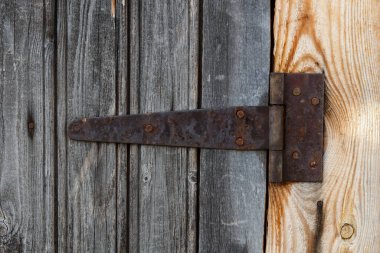 Paslı metal kapı menteşesi. Kapı ahşap bir duvarda..