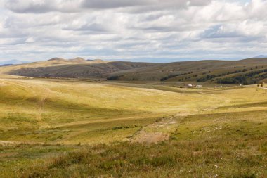 Otlaklı Moğol bozkırları, yurtları ve beyaz bulutlu gökyüzü