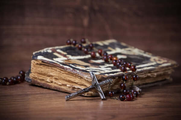 Christian cross necklace next to prayer-book