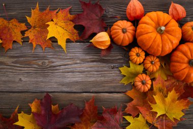 Balkabağı ve dökülen yapraklarla ahşap arka planda. Üst görünüm.