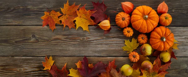Kader met pompoenen en herfstbladeren op houten ondergrond. Bovenaanzicht. — Stockfoto