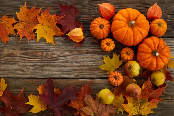 Kader met pompoenen en herfstbladeren op houten ondergrond. Bovenaanzicht. — Stockfoto