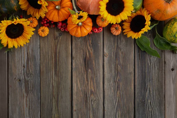Thanksgiving framework. Flowers, pumpkins and fallen leaves on wooden background. Copy space for text. Halloween, Thanksgiving day.