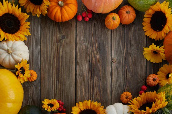 Dankbarkeitsrahmen. Blumen, Kürbisse und abgefallene Blätter auf hölzernem Hintergrund. Kopieren Sie Platz für Text. Halloween, Erntedankfest. Stockbild
