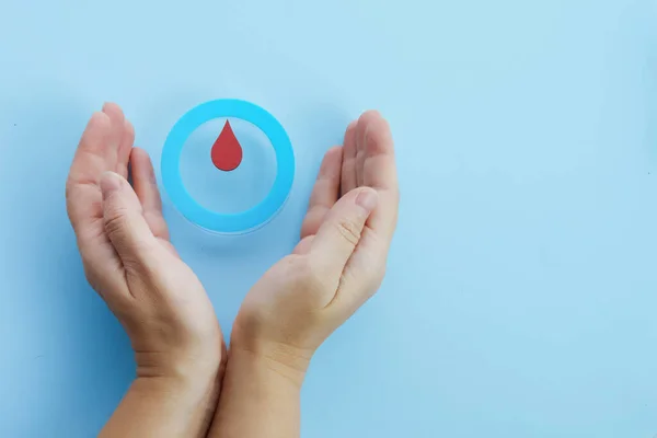 Consciência mundial do dia diabetes. Mãos de mulher com um círculo azul com gota de sangue, símbolo da diabetes — Fotografia de Stock