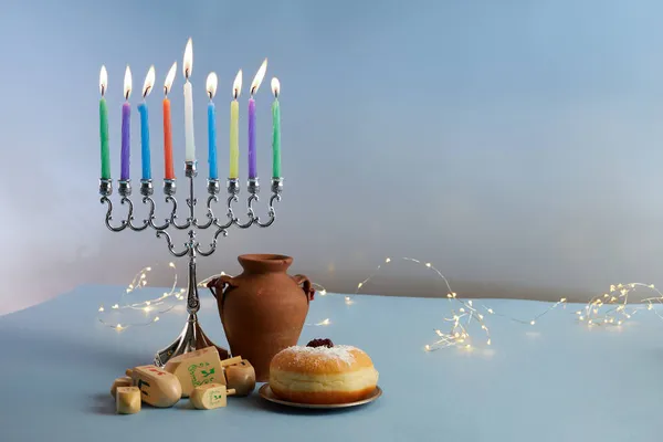 Fiesta judía fondo Hanukkah con menora- candelabros tradicionales, peonza y rosquilla sobre fondo azul — Foto de Stock